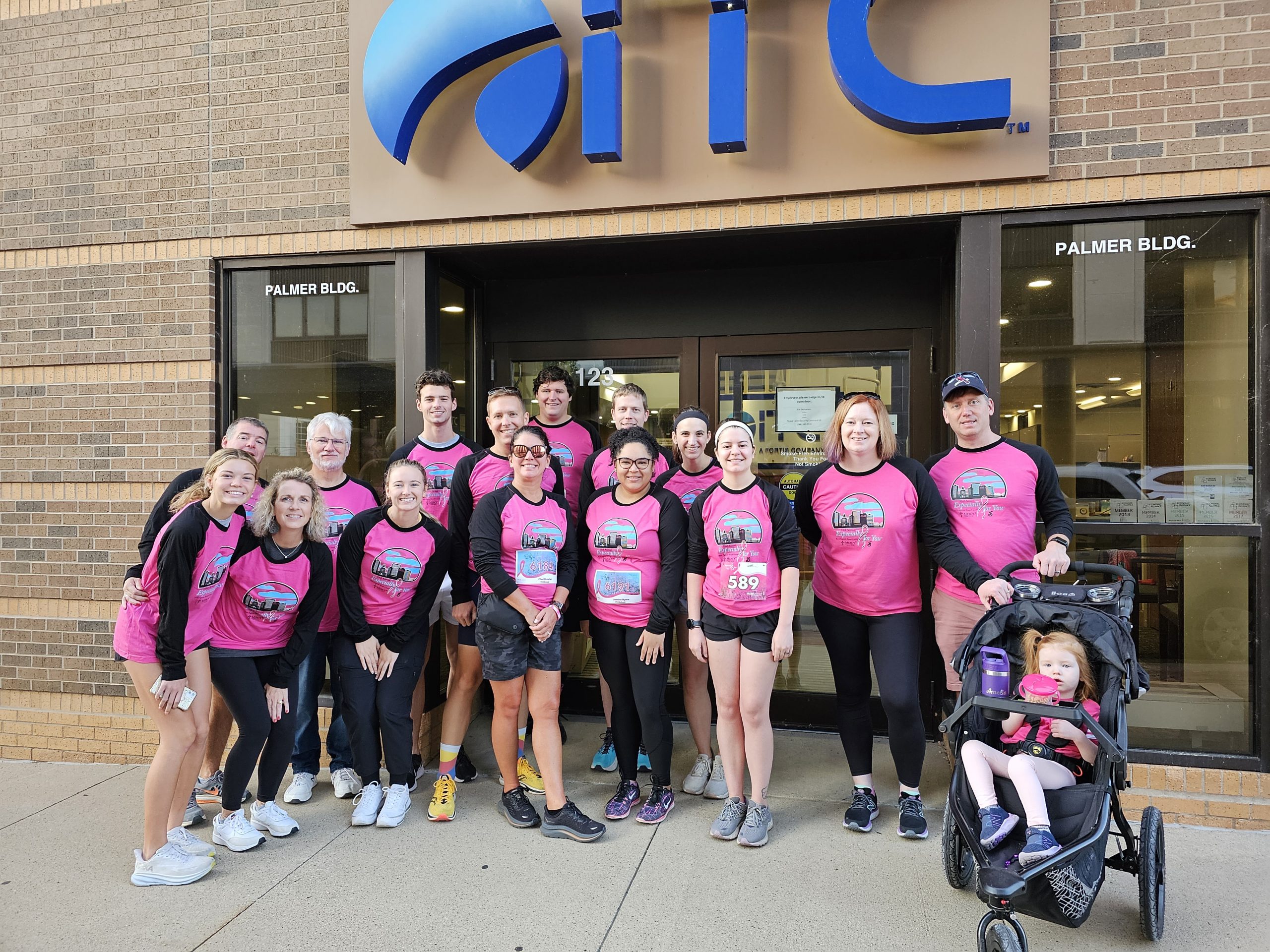 Group of people wearing pink shirts standing outside of ITC building.
